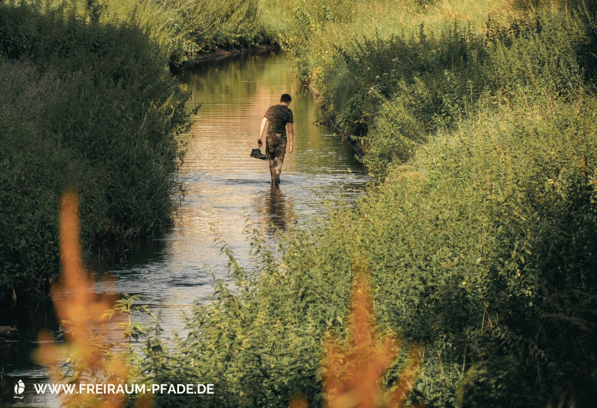 Barfuß durch einen Bach gehen, Schuhe in der Hand – ein Bild für absichtsloses Gehen, kleine Naturmomente und Freiraum
