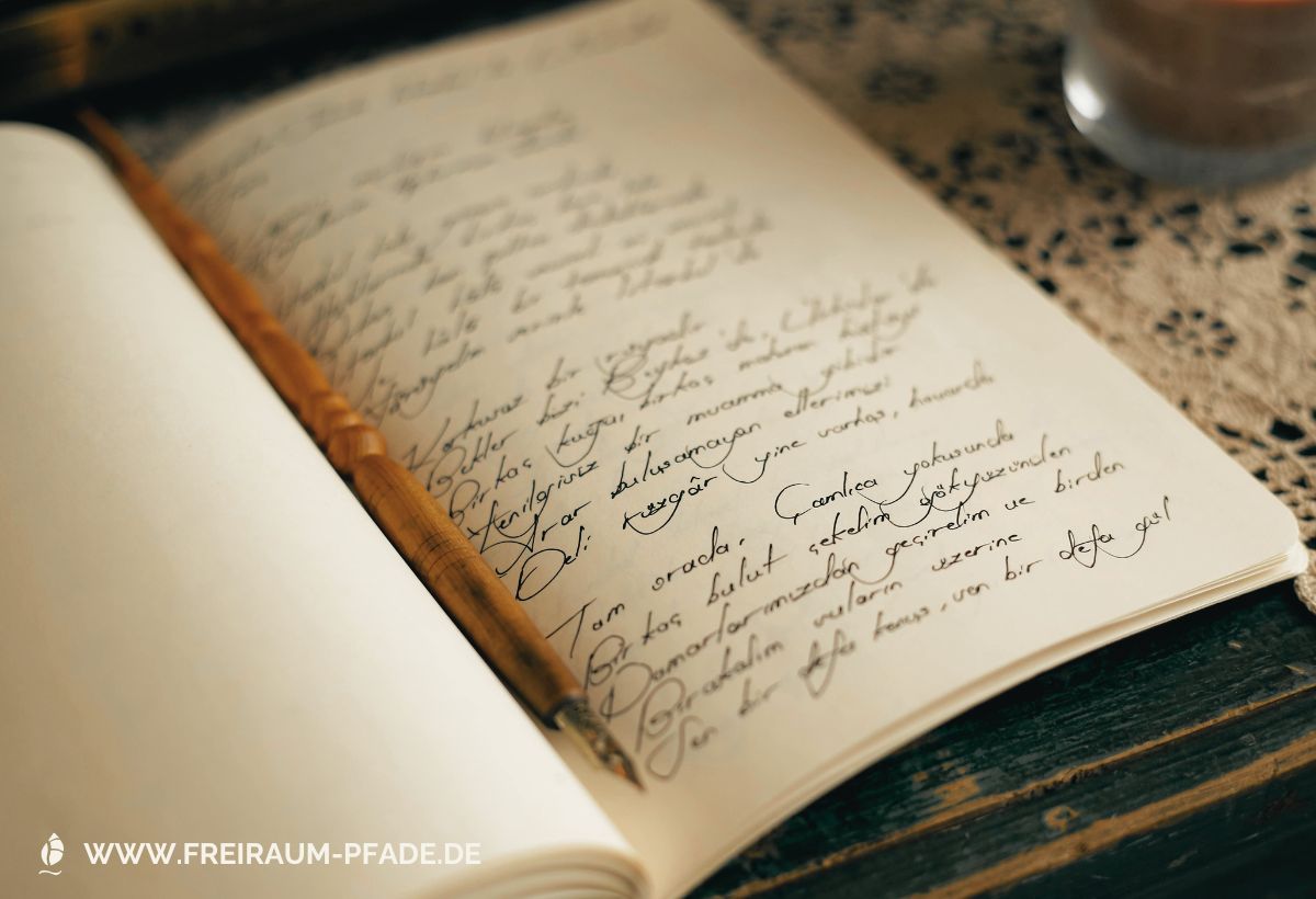 Cremefarbene Seiten in einem Notizbuch, die mit einer geschwungenen, schwarzen Handschrift beschrieben sind; in der Falz des Buches liegt ein aus Holz gedrechselter Füllfederhalter.